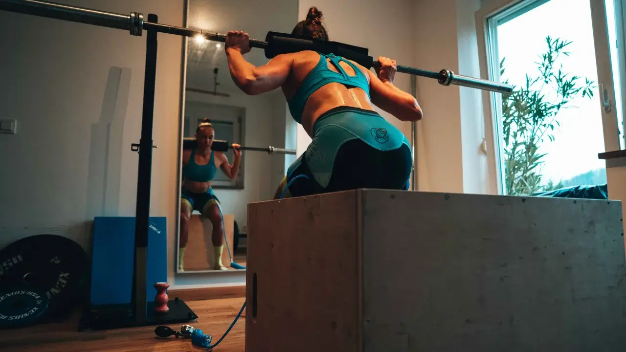 Frau beim Krafttraining für Triathlon, macht Kniebeugen mit Langhantel.