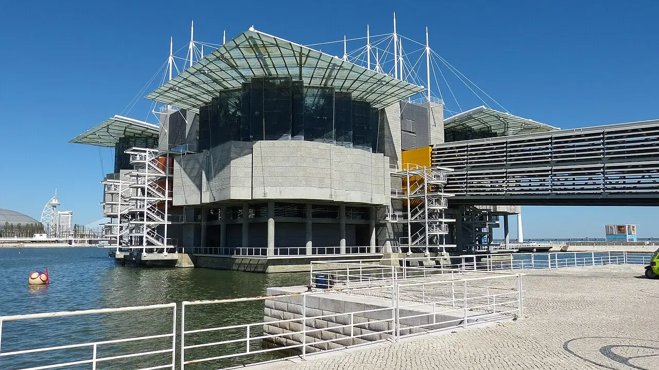 Das moderne Aquarium Lissabon ragt mit seinen Glasdächern und Betonstrukturen über dem Wasser auf.