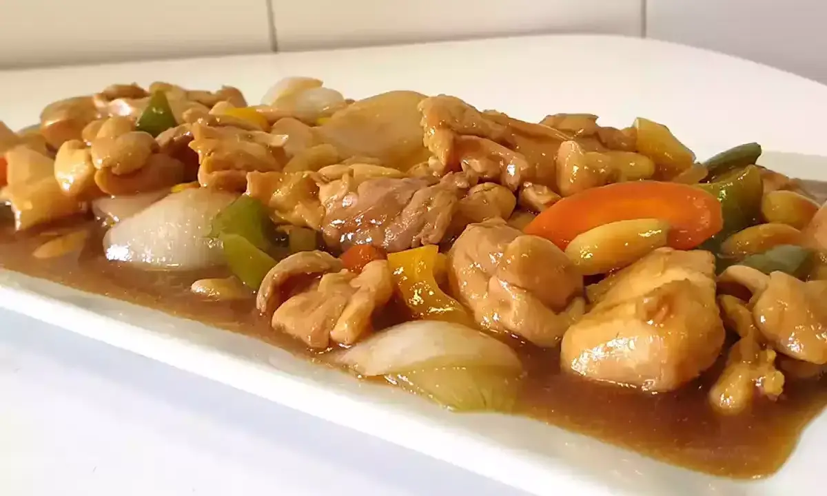 Delicioso pollo con almendras, pimientos y cebolla en una salsa dorada.