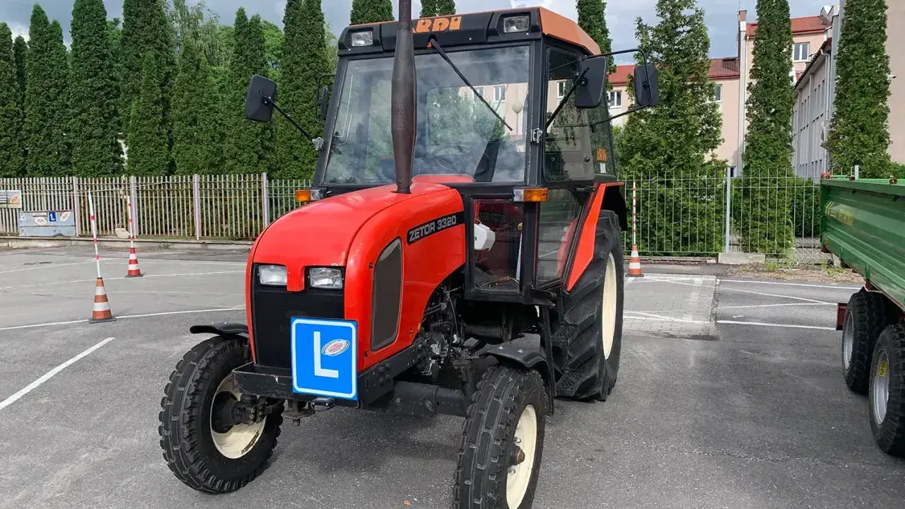 Czerwony traktor Zetor z tabliczką "L" na masce, gotowy do egzaminu na prawo jazdy na traktor.