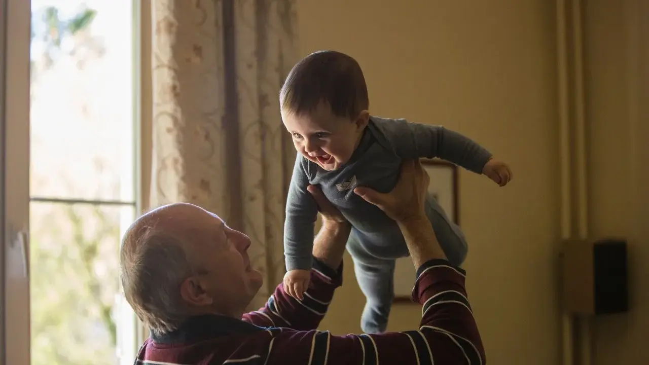 Dziadek podrzuca radosnego wnuka. Czy dziadkowie muszą płacić alimenty za syna? To pytanie, które nie ma związku z tą ciepłą chwilą.