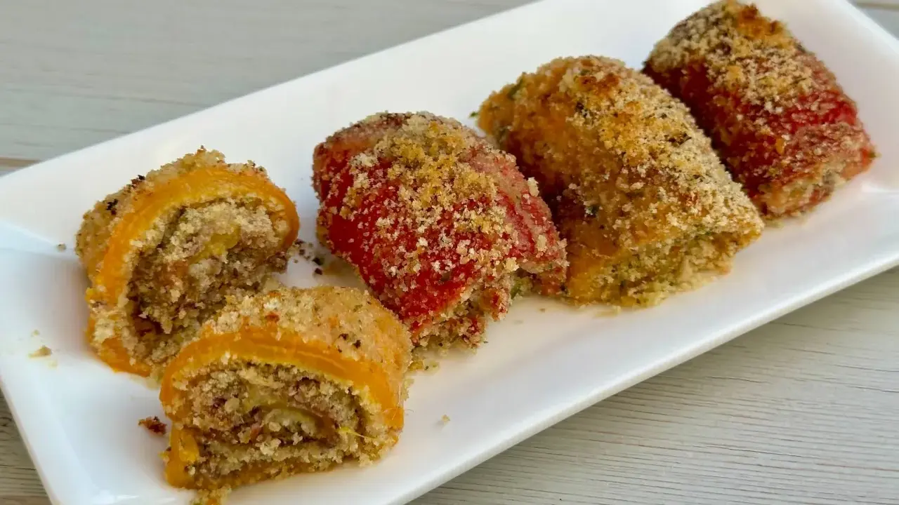 Involtini di peperoni ripieni e gratinati, serviti su un piatto bianco.