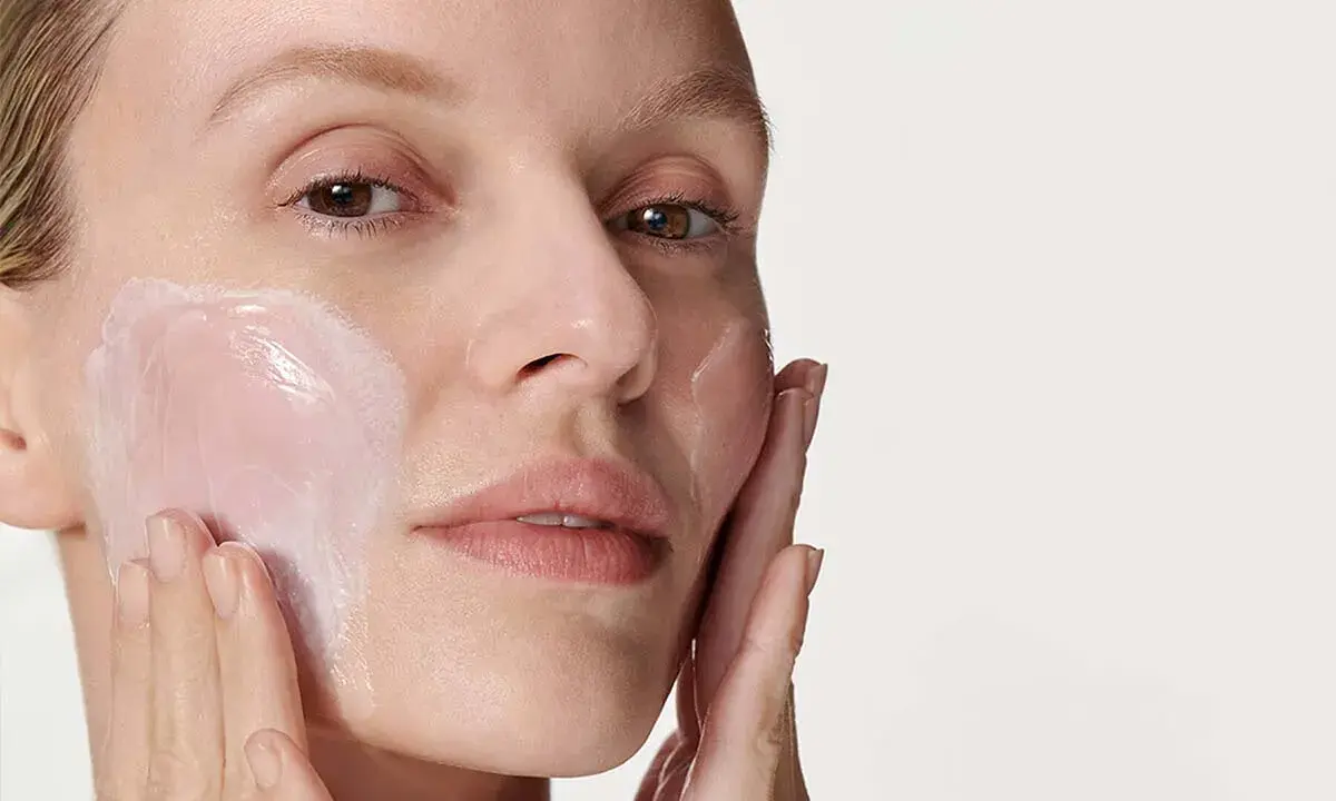 Donna applica delicatamente crema viso con le dita, un gesto semplice per prendersi cura della pelle.