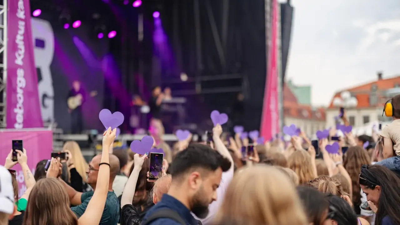 Publik med lila hjärtan och mobiler fångar en konsertupplevelse under ett av Göteborgs evenemang.
