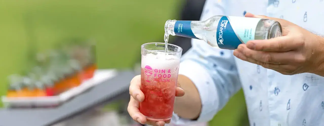 Tonic water wird in ein Glas mit rotem Getränk gegossen. Perfekt, um den Sommerdrink zu mischen.