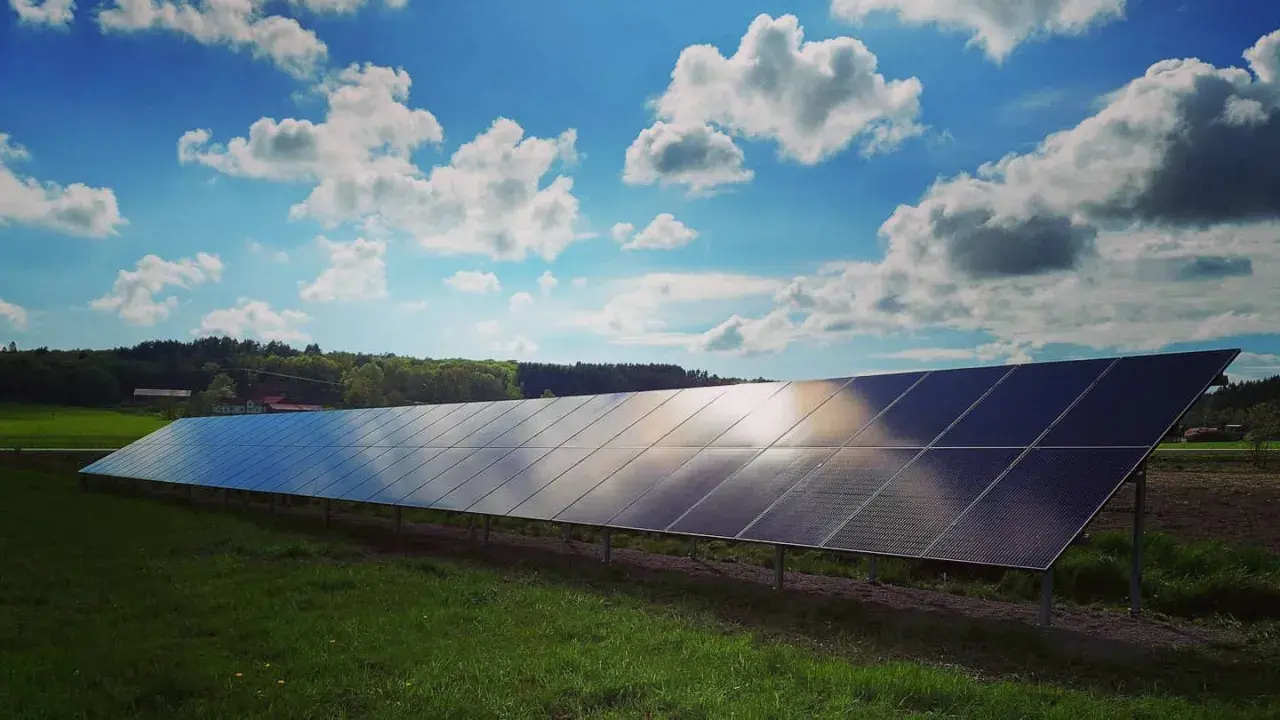 Lång rad solpaneler fångar solljuset under en molnig himmel. Solkraft EMK AB bidrar till en grönare framtid.
