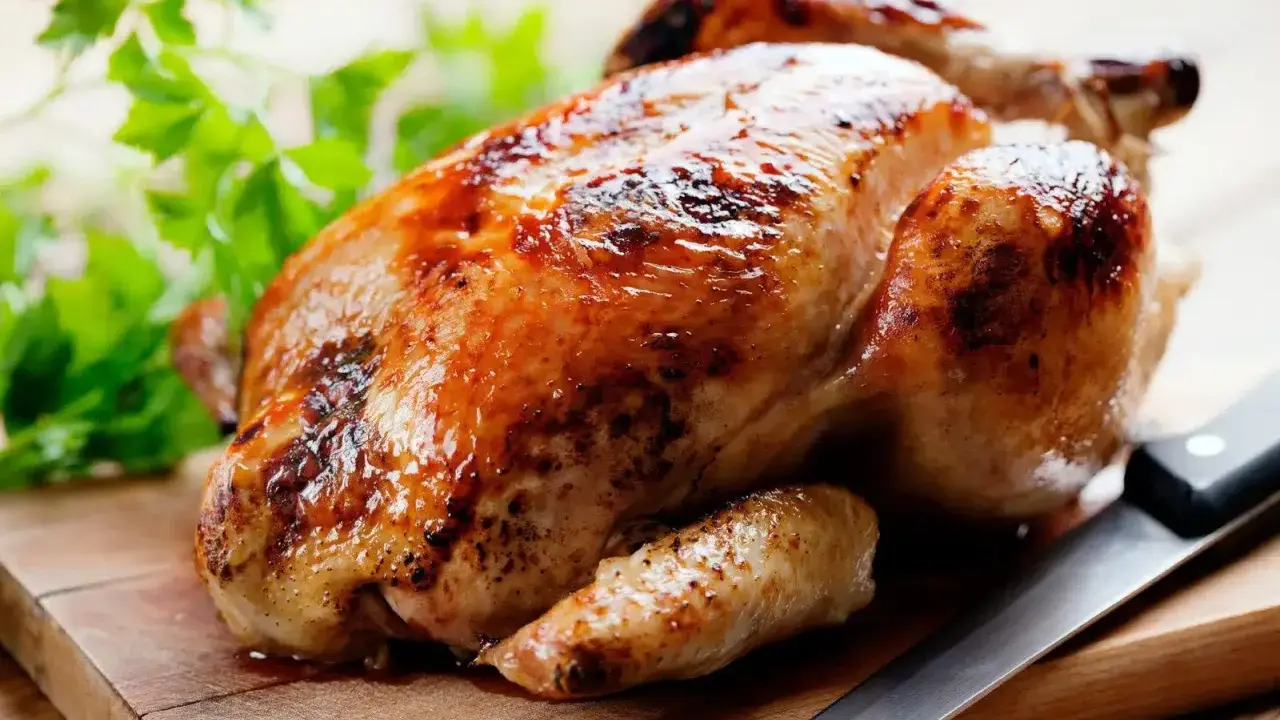 Un appétissant poulet rôti sur une planche en bois, prêt à être dégusté. Quel vin avec poulet rôti ? Un blanc fruité ou un rouge léger serait parfait.