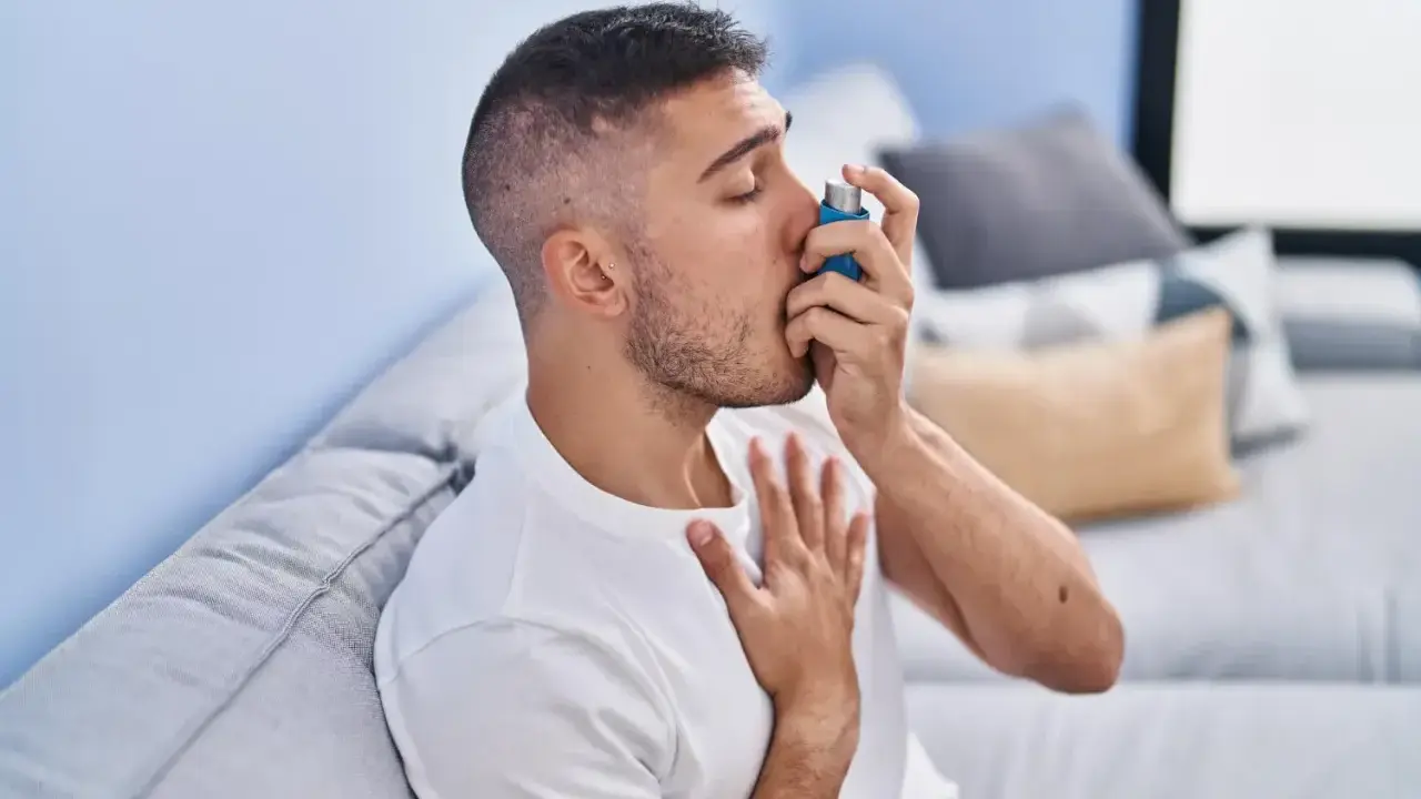 Mężczyzna używa inhalatora, szukając ulgi w objawach astmy. Leki na astmę bez recepty mogą pomóc w łagodzeniu napadów.