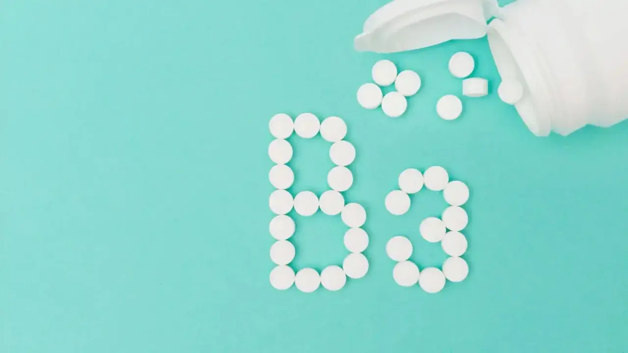 Des pilules blanches forment le "B3" sur fond turquoise. La vitamine B3, c'est quoi ? C'est essentiel pour votre corps.