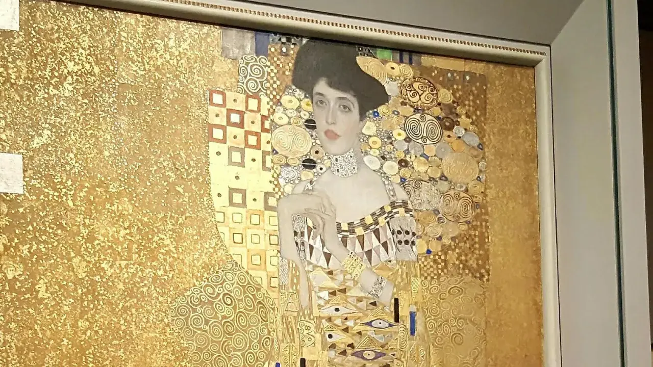 A woman in gold painting, adorned with intricate patterns and jewels, gazes serenely from a gilded background.