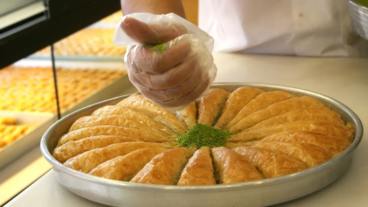 Słodka baklava, co to za przysmak? Warstwy ciasta filo, orzechy i syrop. Posypka z pistacji dodaje uroku.