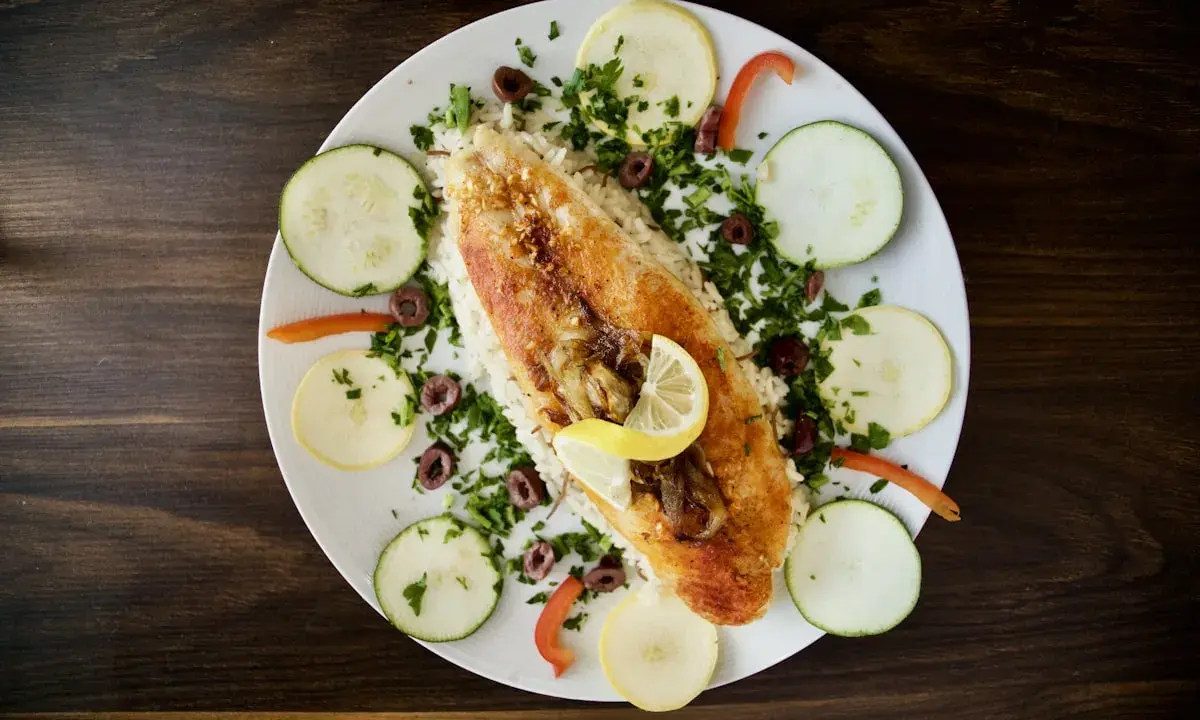Ryba z ryżem, cytryną, oliwkami i warzywami. Pyszne danie w stylu dieta śródziemnomorska.