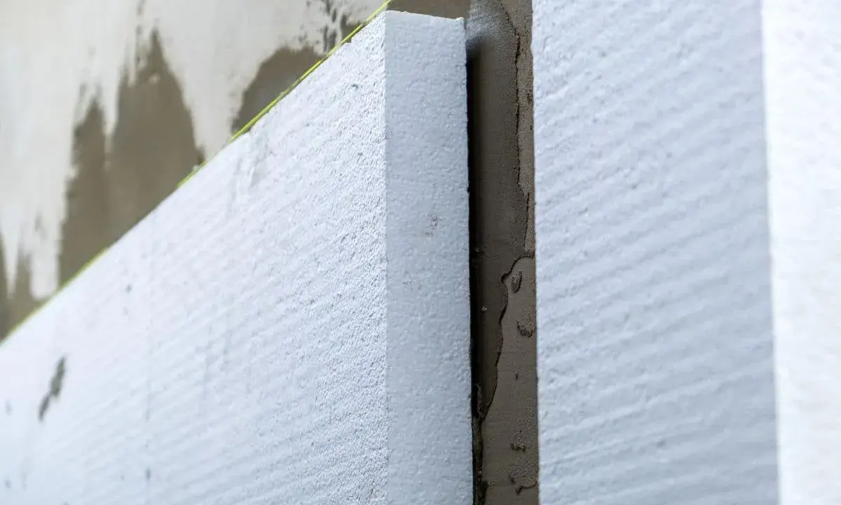 Aislamiento de poliestireno expandido en una pared, paso clave para **edificios eficientes** y confortables.