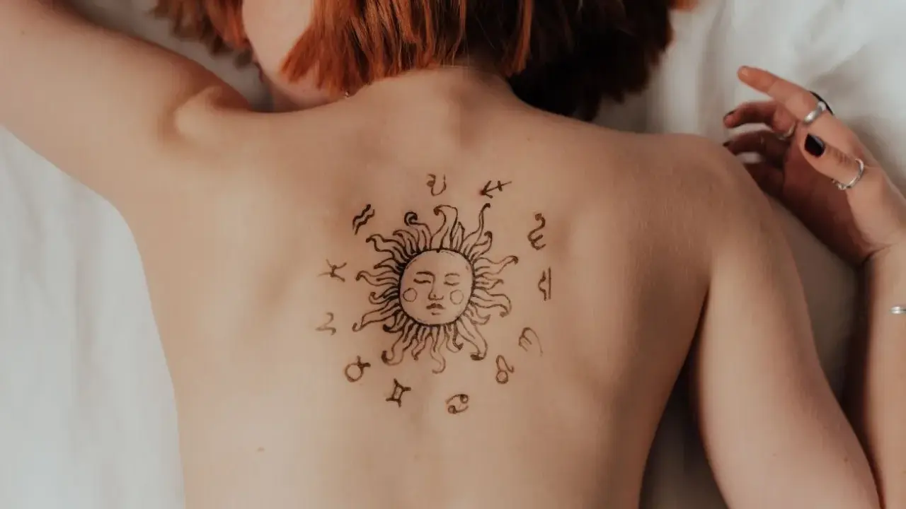 Tatuaż na plecach: słońce otoczone znakami zodiaku. Może symbolizuje ascendent w Lwie, emanujący energią i pewnością siebie.