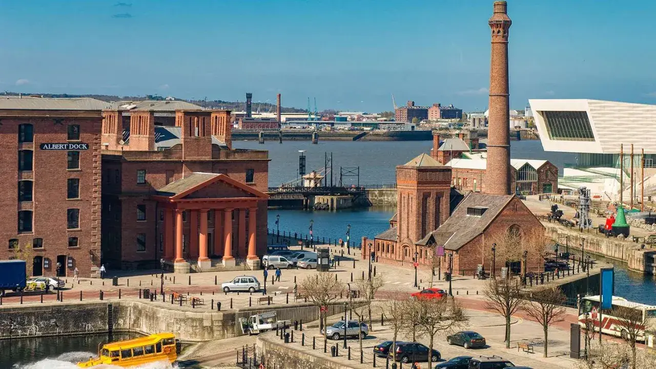 Albert Dock in der Liverpool Stadt, mit einem gelben Amphibienfahrzeug im Wasser und einem hohen Schornstein.