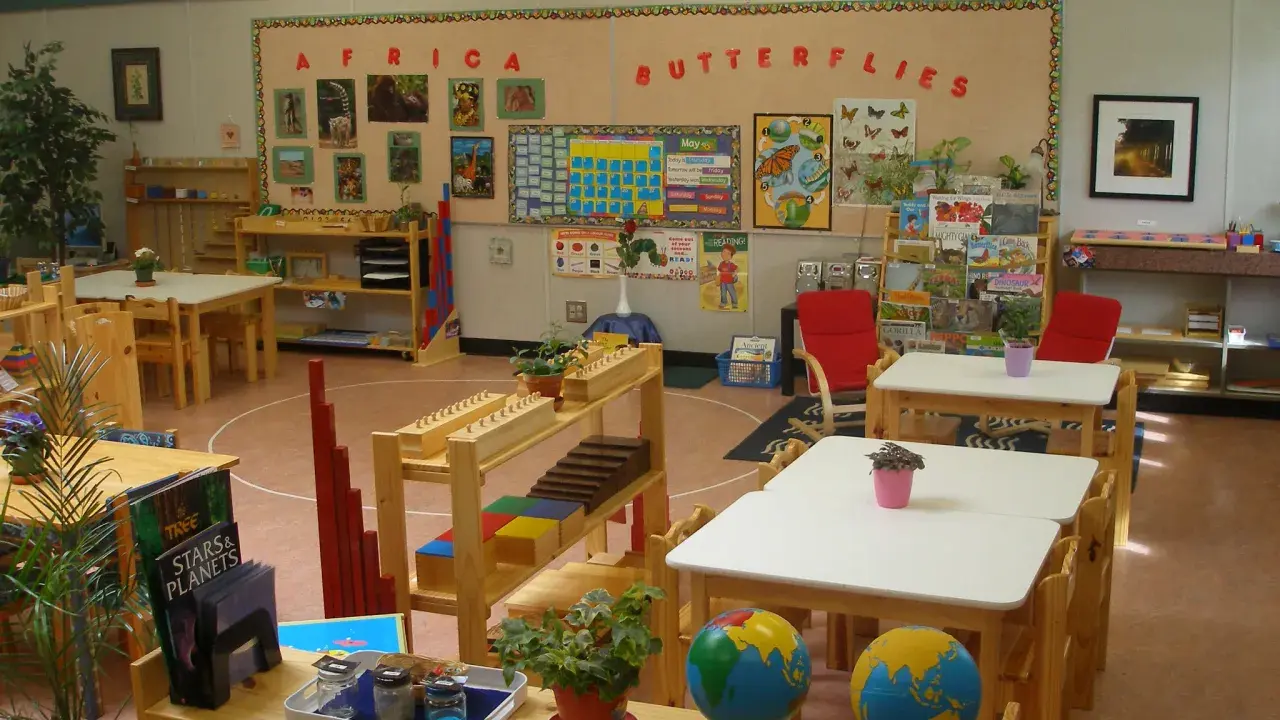 Klasa przygotowana zgodnie z metodą Montessori: globusy, książki o Afryce i motylach, materiały edukacyjne na półkach.
