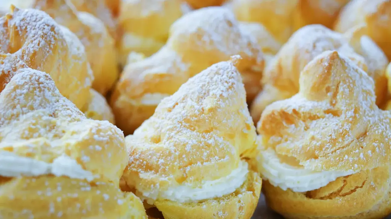 Une assiette de choux à la crème, saupoudrés de sucre glace. Ces petites merveilles de chou patisserie sont prêtes à être dégustées.