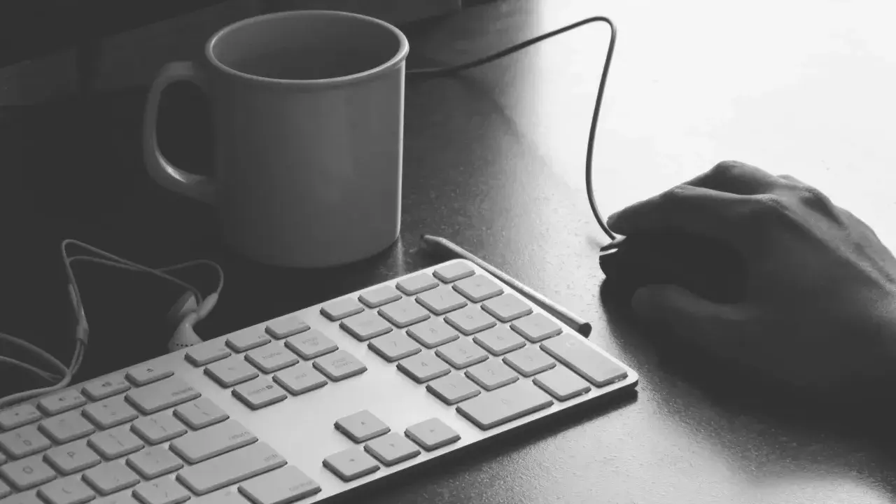 Ręka programisty nad klawiaturą, kubek kawy i myszka. Czas na programowanie aplikacji.