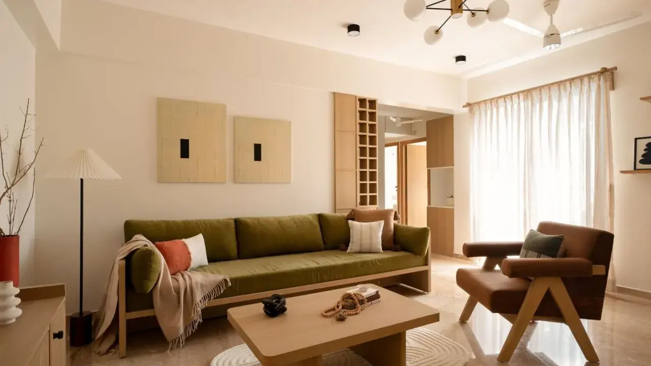 Soggiorno in stile Japandi con divano verde, poltrona in pelle, tavolino in legno e opere d'arte minimaliste.