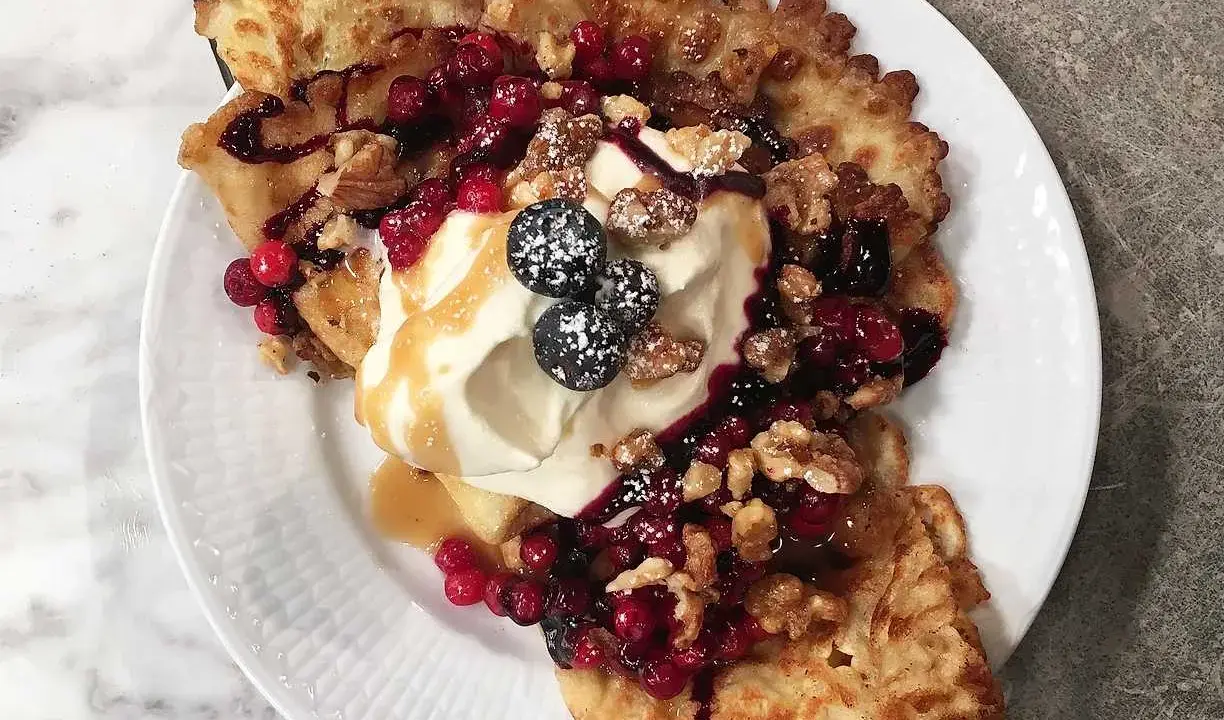 Frasiga pannkakor toppade med vispgrädde, bär, nötter och sirap. En härlig frukost eller dessert.