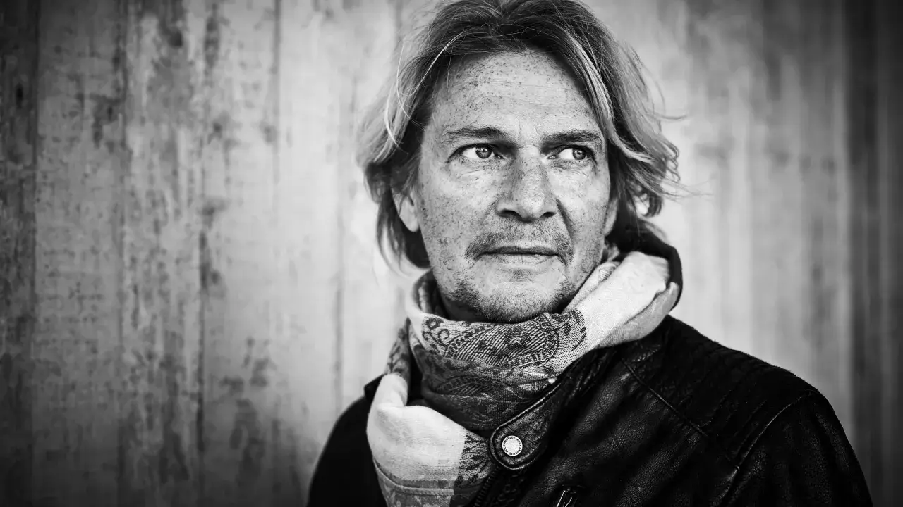 Tommy Nilsson, med sitt karaktäristiska utseende och en scarf, redo att inta scenen med sitt band.