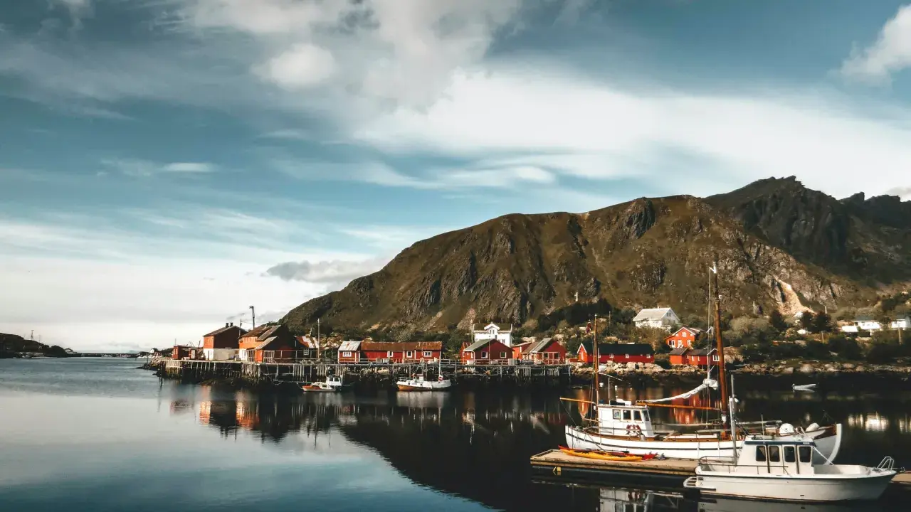 Malowniczy norweski port z czerwonymi domkami i łodziami. Czy do Norwegii trzeba mieć paszport? Sprawdź przed podróżą!