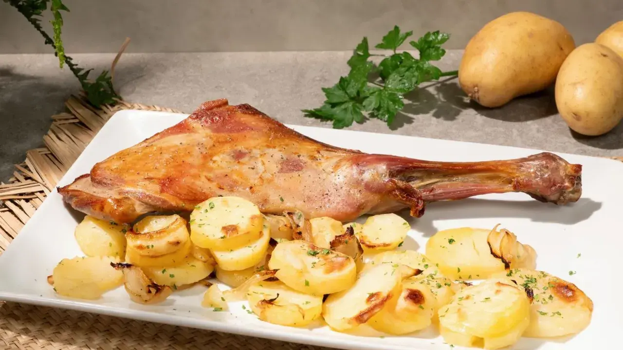 Paletilla de cordero al horno dorada y jugosa, acompañada de patatas panadera y perejil fresco. Un plato principal delicioso.