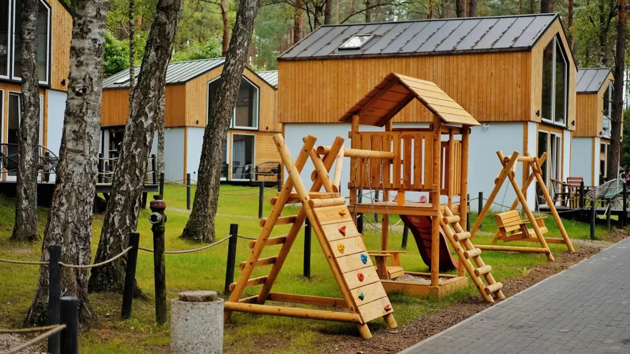 Drewniany plac zabaw z domkami w tle – idealne bory tucholskie atrakcje dla dzieci.