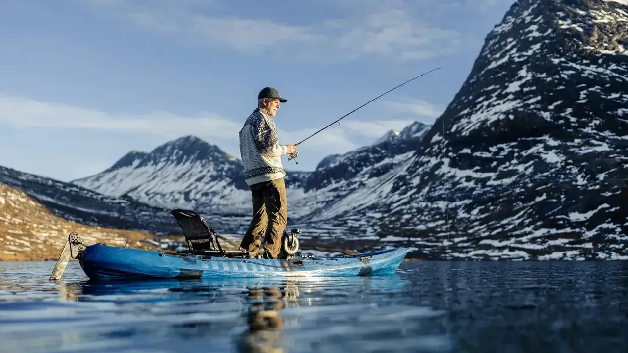 Man fiskar från en kajak i en fjällsjö. Frågan är hur långt paddlar man på en dag i sådan vacker natur?