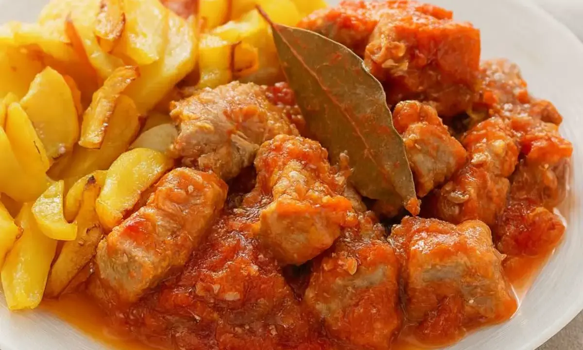 Sabroso magro con tomate, trozos de carne tierna en salsa de tomate, acompañados de patatas fritas doradas.