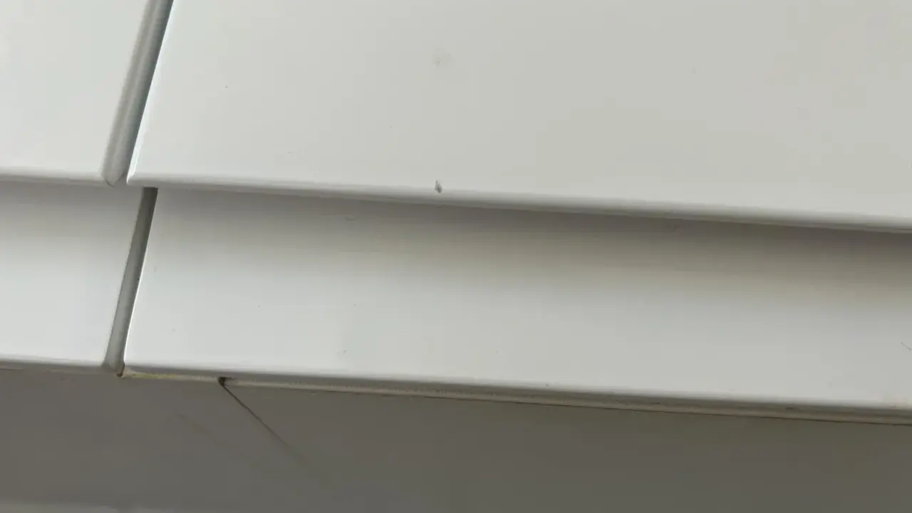 Detalle de un mueble lacado blanco con pequeños arañazos, listo para reparar.