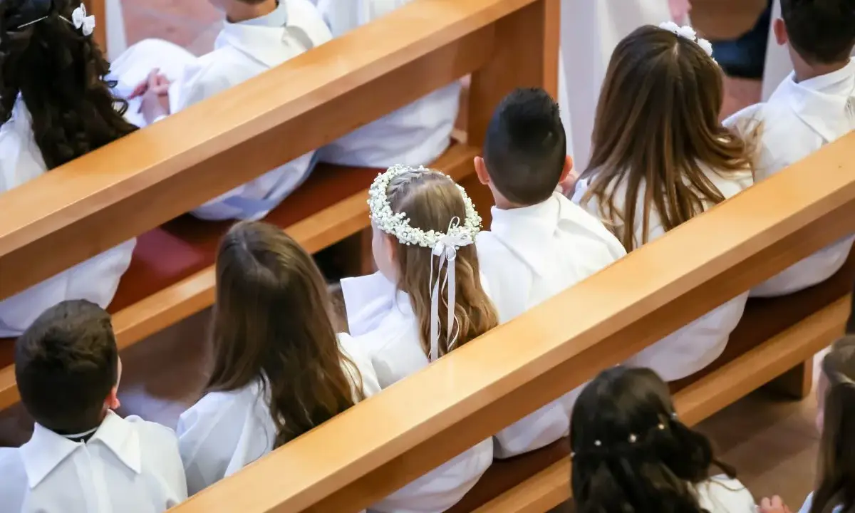 Dzieci w bieli, gotowe na Komunię Świętą. Wianek na głowie dziewczynki to piękne życzenia na komunie.