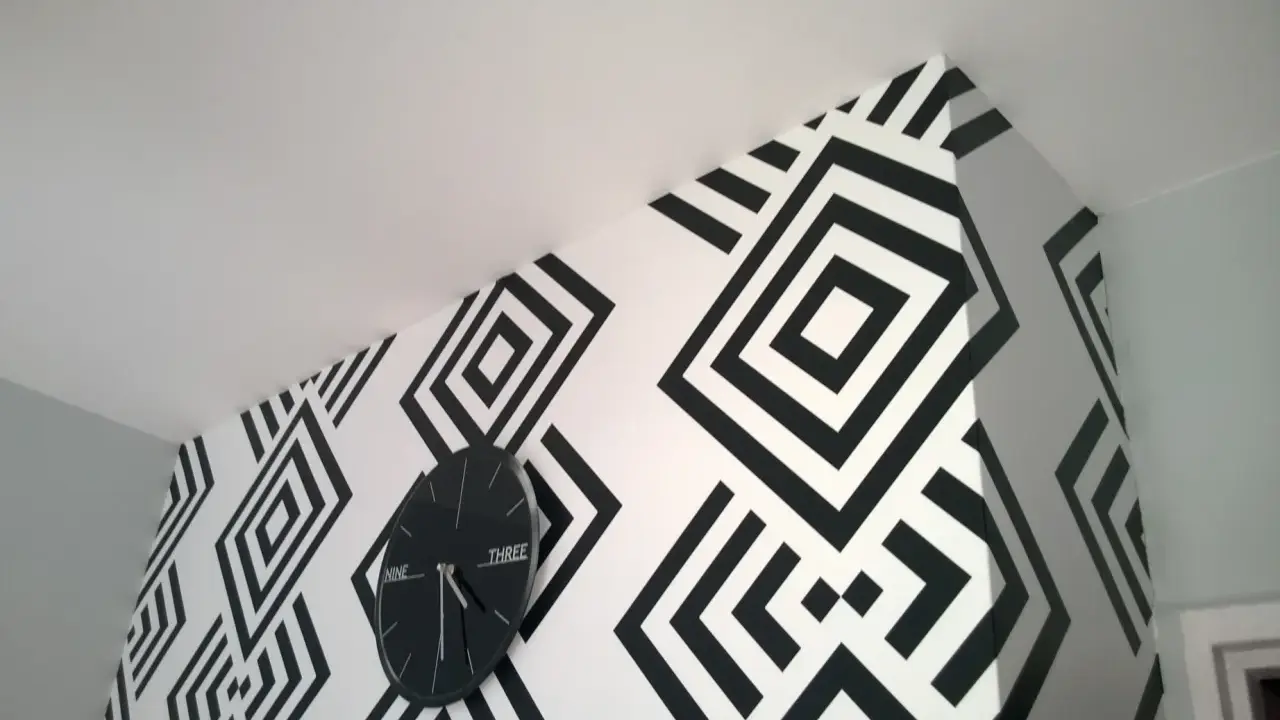 Nowoczesne tapety biało czarne z geometrycznym wzorem rombów. Zegar ścienny w czarnej ramie idealnie komponuje się z aranżacją.
