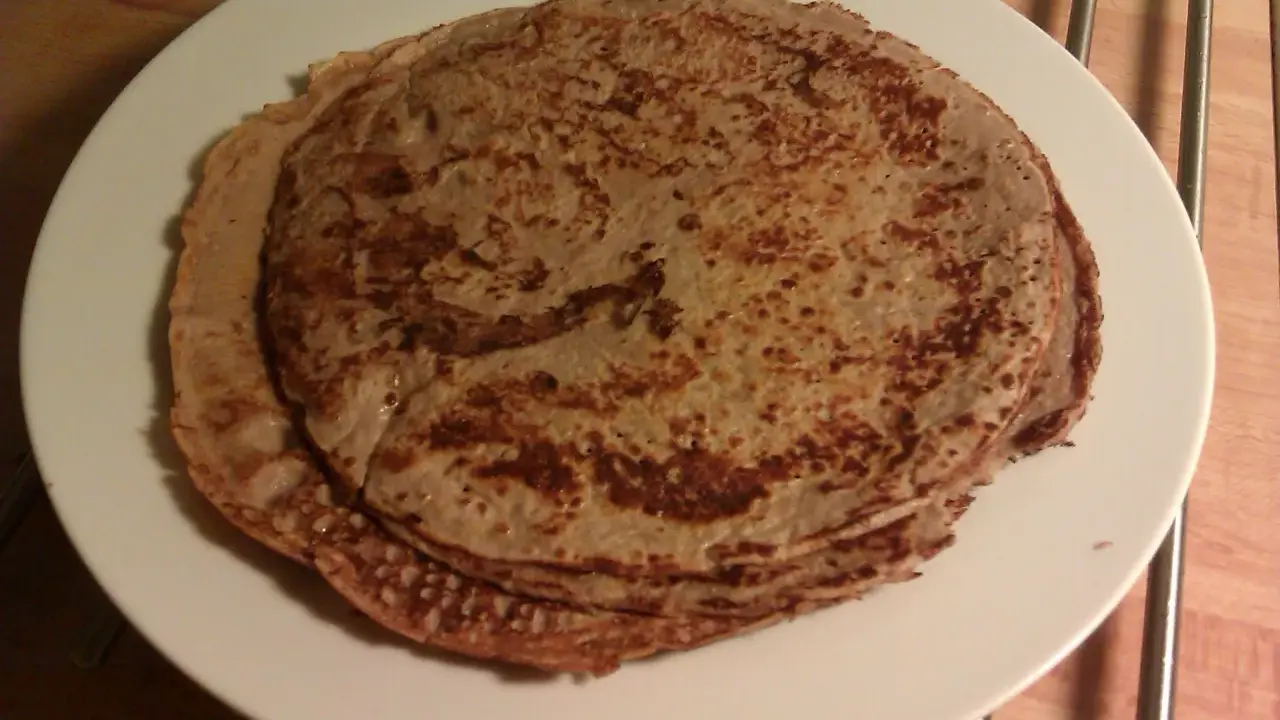 En hög med tunna pannkakor på en vit tallrik. Perfekt för en mysig frukost eller som frukost tips.