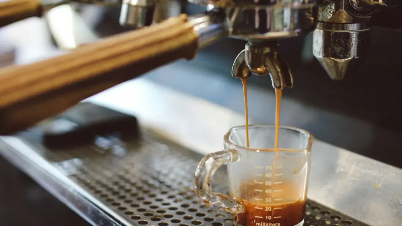 Espresso spływa do szklaneczki. Czy ekspres do kawy pobiera dużo prądu? To zależy od modelu, ale ten wygląda na profesjonalny.