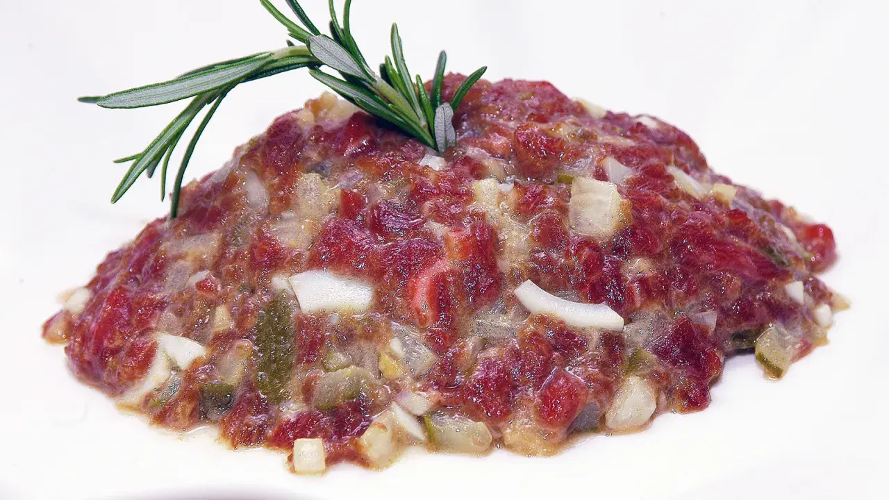 Delicioso steak tartar de los Hermanos Torres, con carne picada, cebolla, pepinillos y un toque de romero.