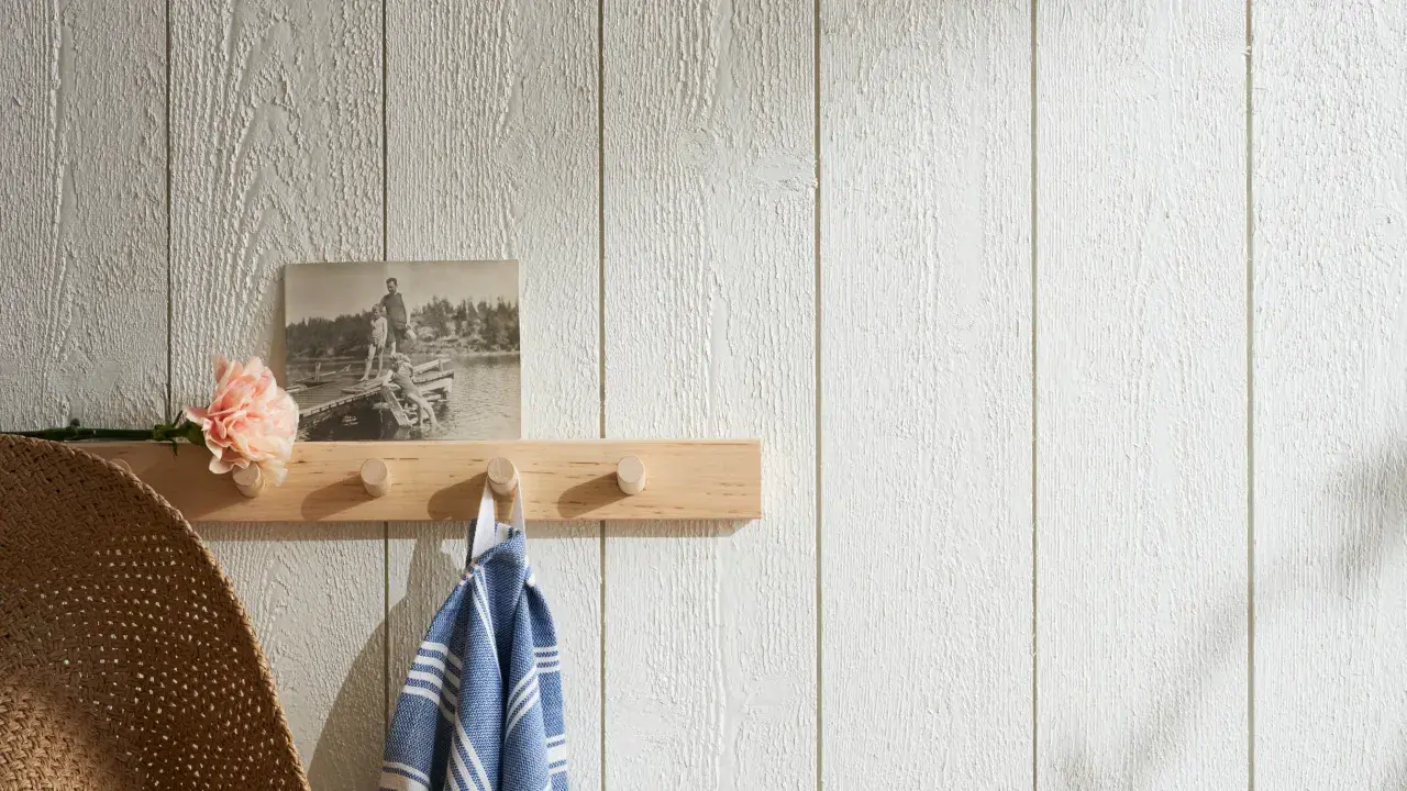 En träpanel inomhus inspiration med en ljus trähylla, en gammal bild, en blomma och en handduk.