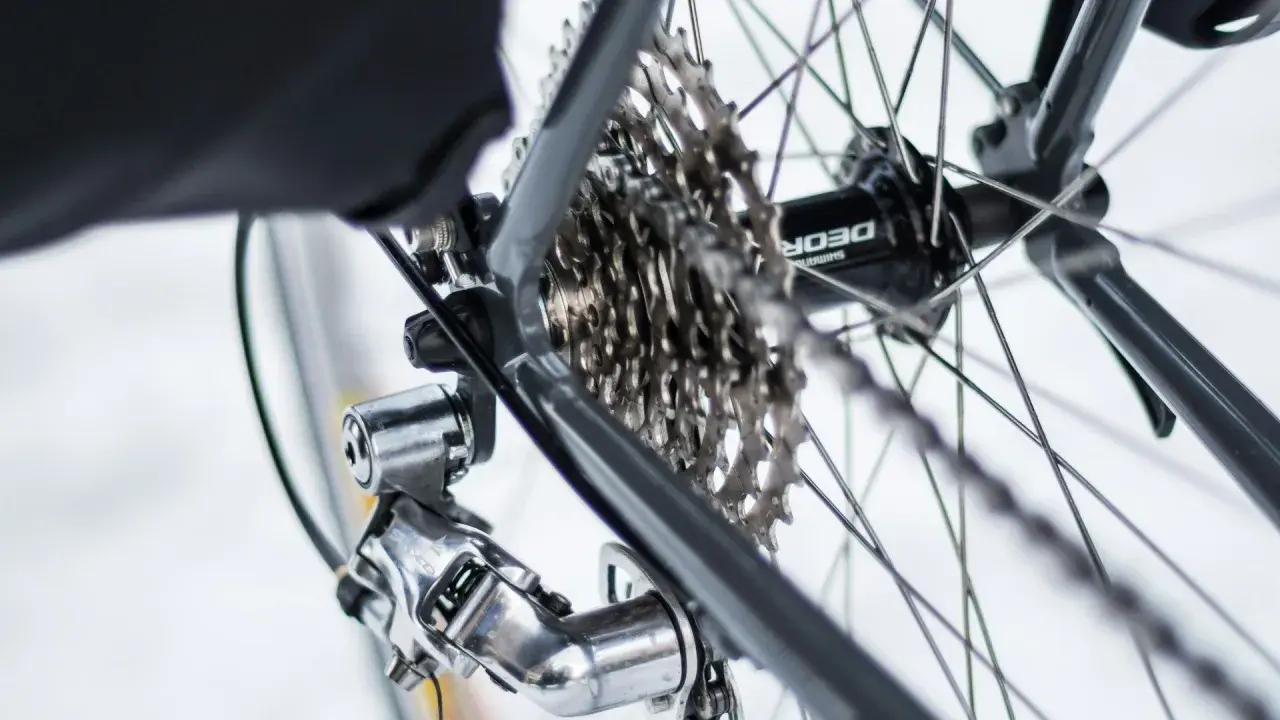 Błyszczący osprzęt Shimano Deore na tylnej przerzutce i kasecie rowerowej.