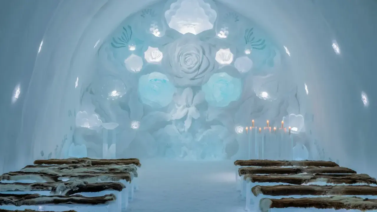 Vacker iskyrka i ett igloo hotell Sverige. Bänkar av is med renskinn, isrosor och levande ljus skapar en magisk atmosfär.