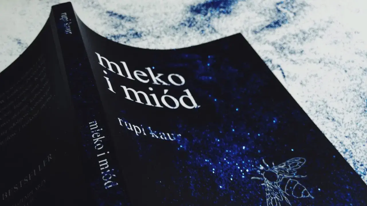 Okładka książki "Mleko i miód" Rupi Kaur z motywem pszczoły na granatowym tle w gwiazdy.