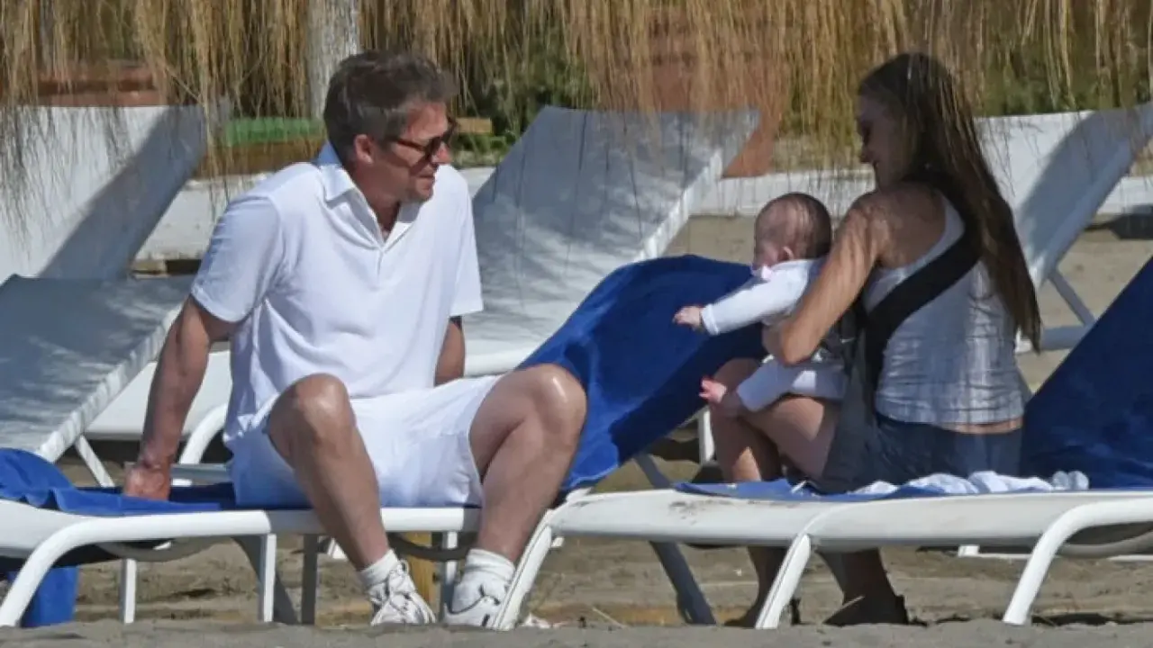 Hugh Grant njuter av stranden med sitt barn och en kvinna.