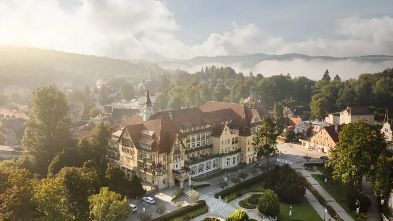 Sanatorium Polonia w Kudowie Zdroju, z pięknymi pokojami i otoczeniem, w mglisty poranek.