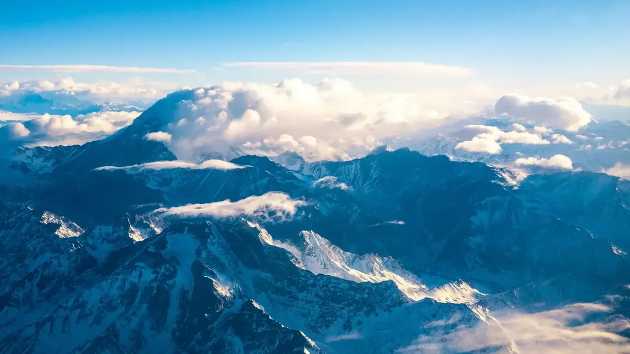 Majestatyczne góry z Aconcagua, skąpane w słońcu, otoczone chmurami. Widok z lotu ptaka na ośnieżone szczyty.