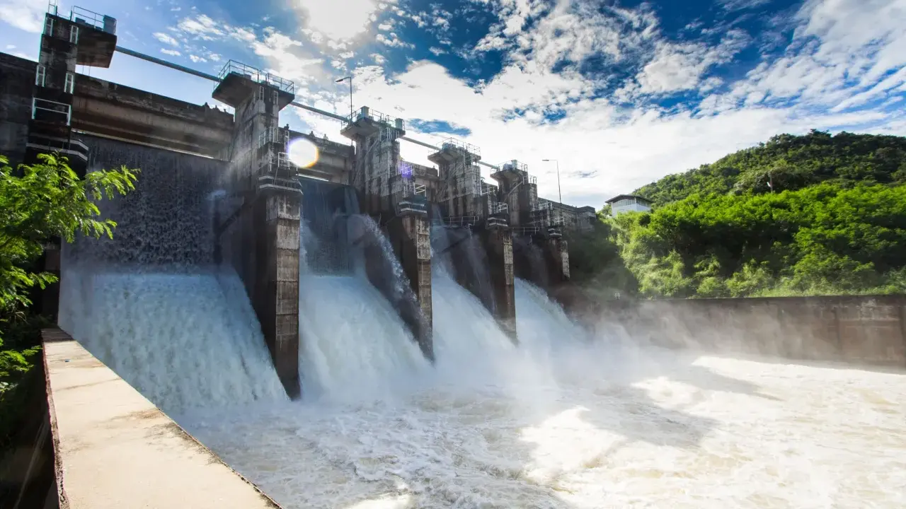 Ein Damm mit mehreren offenen Schleusen, aus denen kräftig Wasser strömt. Ein Beispiel für erneuerbare Energien durch Wasserkraft.
