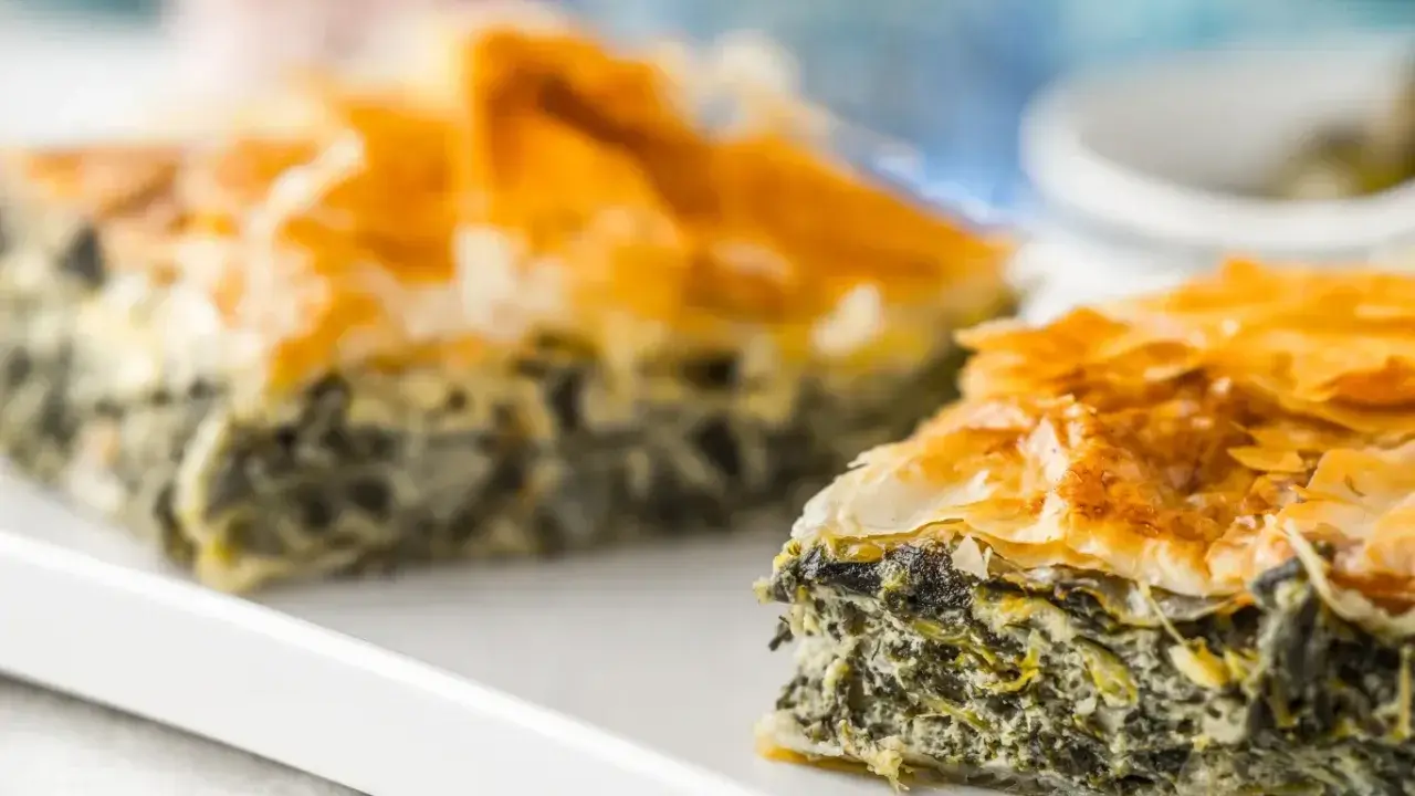 Chrupiąca spanakopita z warstwami ciasta filo i zielonym nadzieniem ze szpinaku i sera.