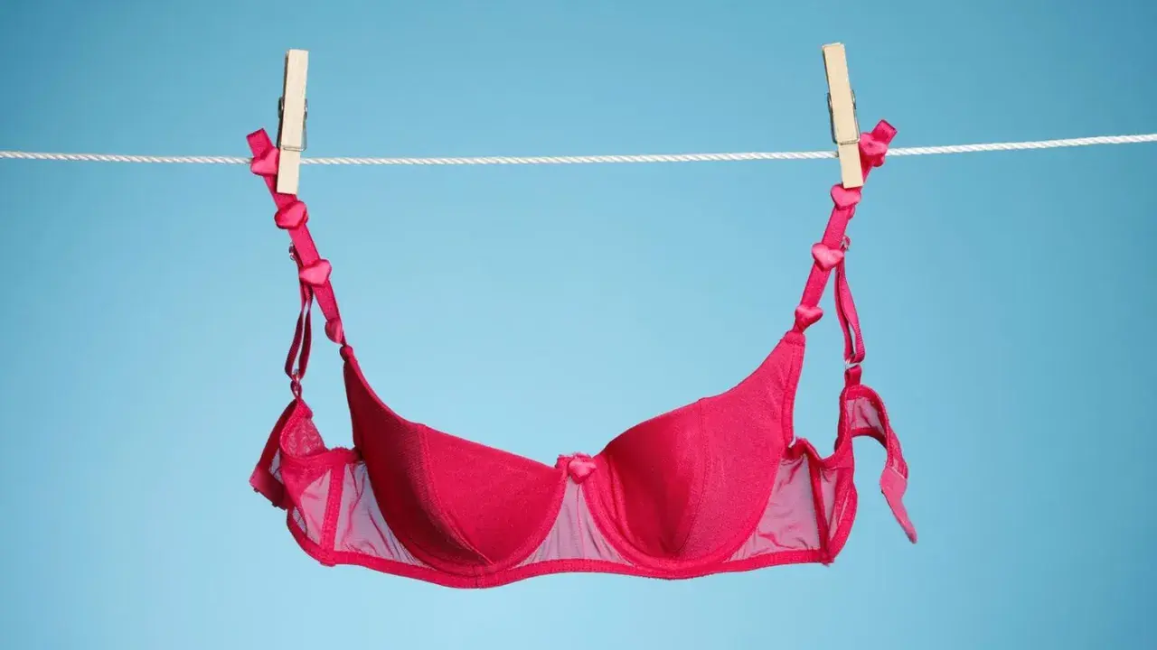 Ein roter BH mit Herzchen-Trägern trocknet an der Wäscheleine. Frisch gewaschen und bereit für den nächsten Einsatz.