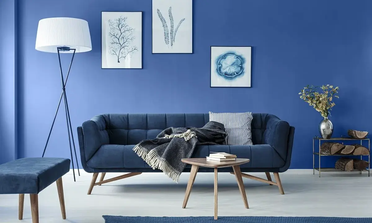 Sofa i ściany w odcieniach koloru niebieskiego. Na ścianie obrazy z motywami morskimi.