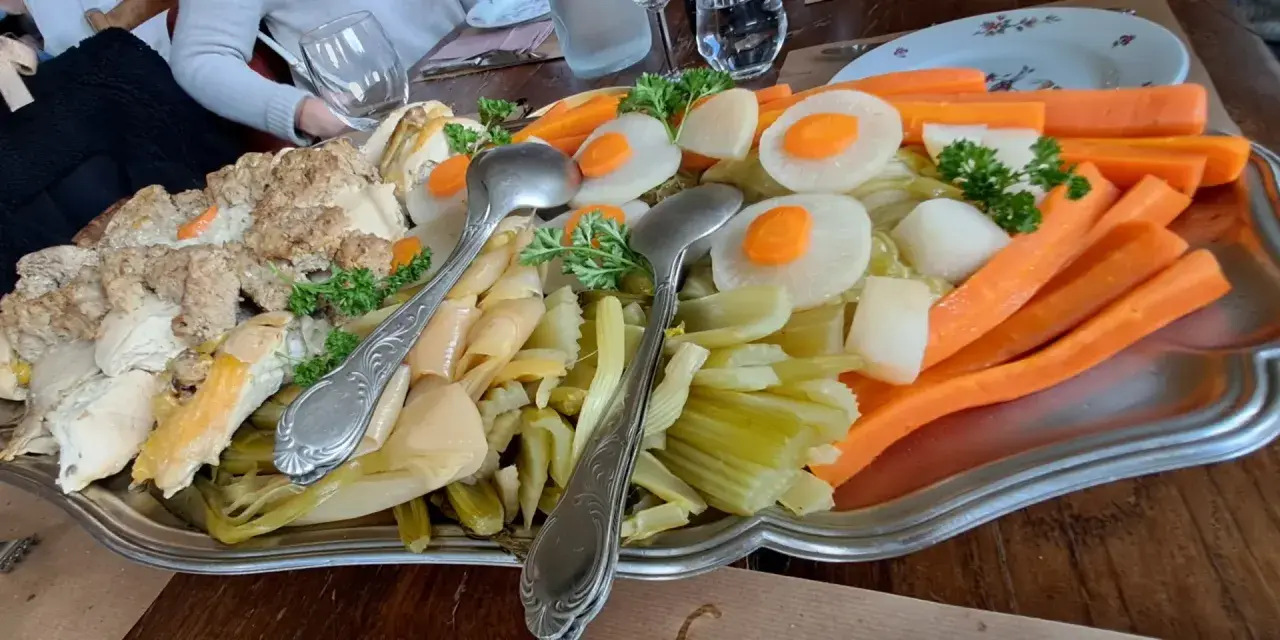 Plat généreux d'un restaurant du terroir : viandes, légumes racines et légumes verts, prêt à être dégusté.
