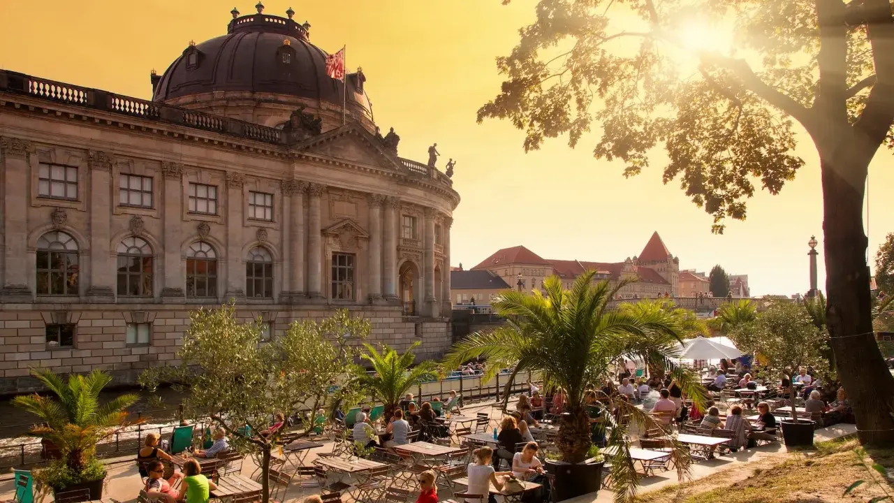 En solig eftermiddag vid en uteservering i Berlin, med en imponerande byggnad i bakgrunden. Kanske en paus innan nattåg Berlin.