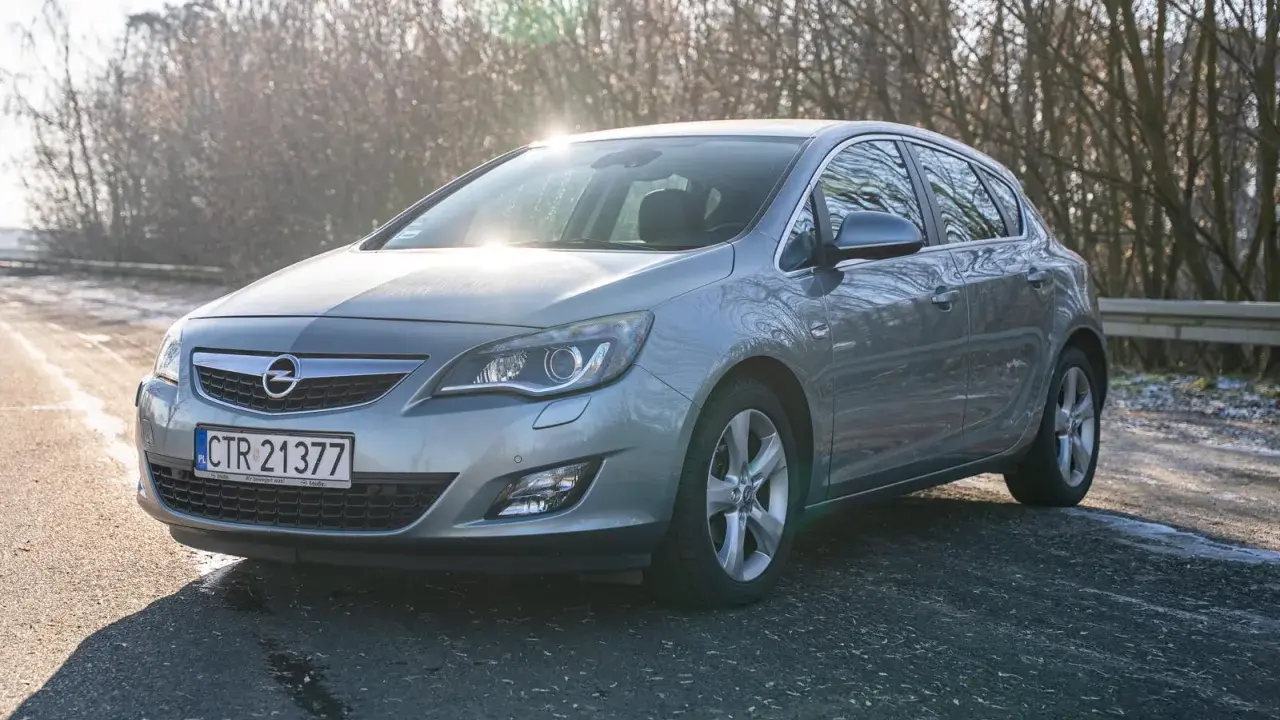 Szary Opel Astra z silnikiem 1.7 cdti zaparkowany na poboczu drogi, w tle drzewa i słońce.